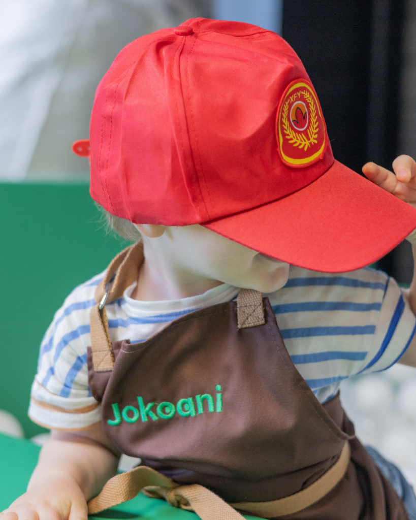 Enfant avec tablier Jokoani et casquette de pompier